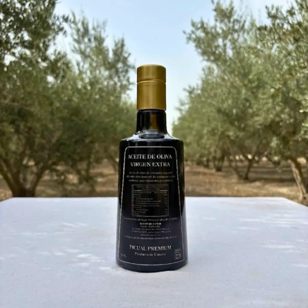 Botella de aceite Picual de 500 ml de espaldas con el olivar de fondo