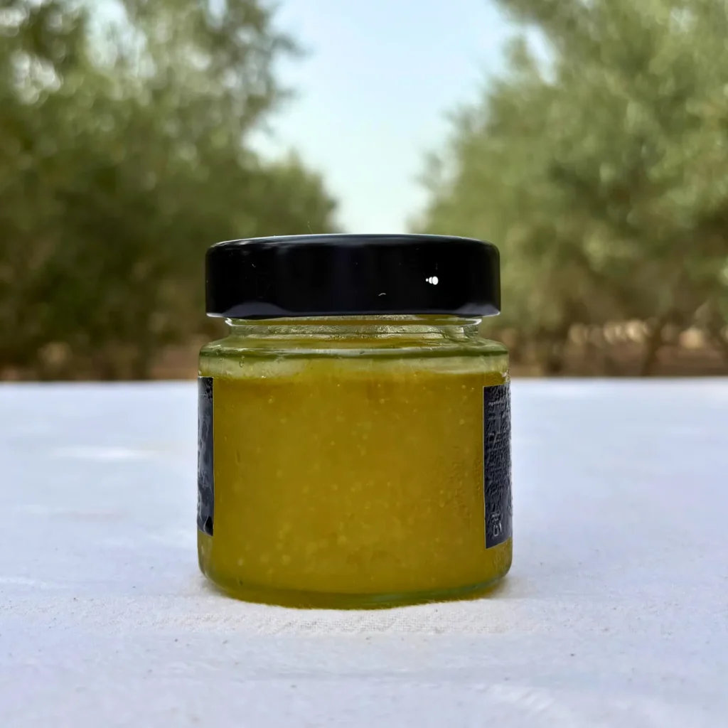 Tarro de mermelada de AOVE con la etiqueta a la vista sobre una mesa en el olivar